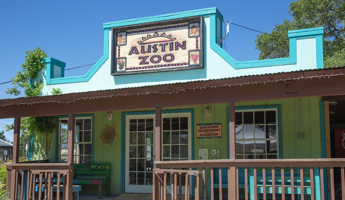 The featured image is a photo of the Austin Zoo front porch with some trees in the background.